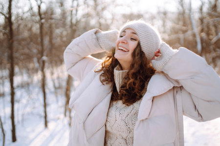 Young woman in winter style clothes walking in the snowy park. Winter fashion, holidays.の写真素材