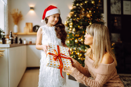 Happy mom and her cute daughter girl exchanging gifts. Merry Christmas and Happy Holidays.の写真素材