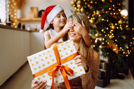 Happy mom and her cute daughter girl exchanging gifts. Merry Christmas and Happy Holidays.の写真素材