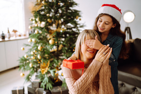 Happy mom and her cute daughter girl exchanging gifts. Merry Christmas and Happy Holidays.の写真素材
