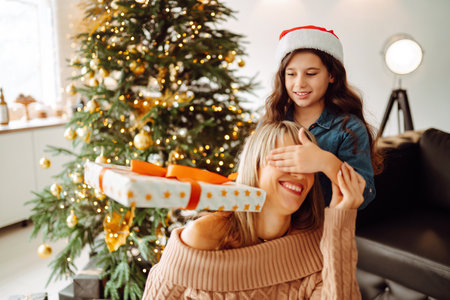 Happy mom and her cute daughter girl exchanging gifts. Merry Christmas and Happy Holidays.の写真素材