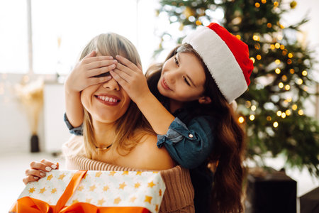 Happy mom and her cute daughter girl exchanging gifts. Merry Christmas and Happy Holidays.の写真素材