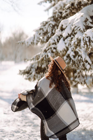Pretty Woman holding a giftbox with red ribbon in the winter park. Happy winter time. new year's.の写真素材