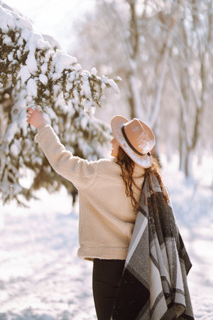 Beautiful woman standing among snowy trees and enjoying first snow. Happy winter time. Christmas.の写真素材