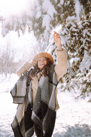 Beautiful woman standing among snowy trees and enjoying first snow. Happy winter time. Christmas.の写真素材