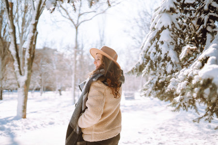 Beautiful woman standing among snowy trees and enjoying first snow. Happy winter time. Christmas.の写真素材