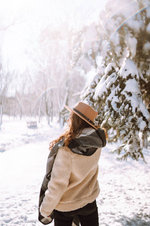 Beautiful woman standing among snowy trees and enjoying first snow. Happy winter time. Christmas.の写真素材