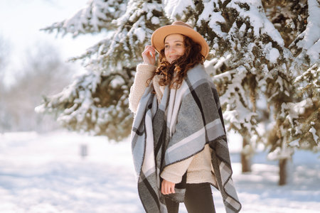 Beautiful woman standing among snowy trees and enjoying first snow. Happy winter time. Christmas.の写真素材