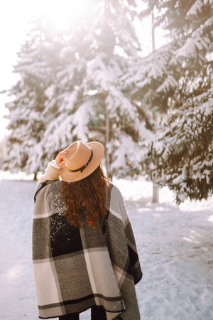 Beautiful woman standing among snowy trees and enjoying first snow. Happy winter time. Christmas.の写真素材