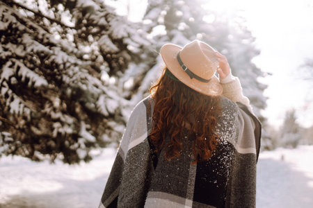 Beautiful woman standing among snowy trees and enjoying first snow. Happy winter time. Christmas.の写真素材
