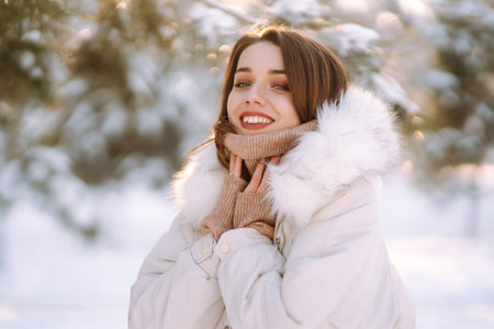 Beautiful woman in winter clothes posing in a snowy park. Young lady walking in a sunny winter day.の写真素材