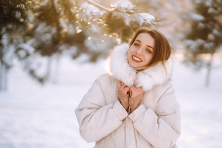 Beautiful woman in winter clothes posing in a snowy park. Young lady walking in a sunny winter day.の写真素材