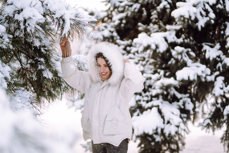 Beautiful woman in winter clothes posing in a snowy park. Young lady walking in a sunny winter day.の写真素材
