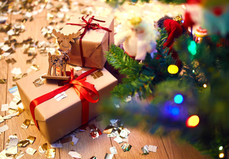 Beautiful Christmas gift boxes with red ribbon on floor near fir tree in room. Luxury New Year giftsの写真素材