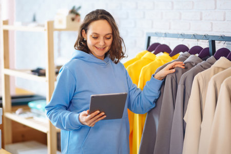 Small business owner, entrepreneur, seller using tablet checking ecommerce clothing store orders.の写真素材