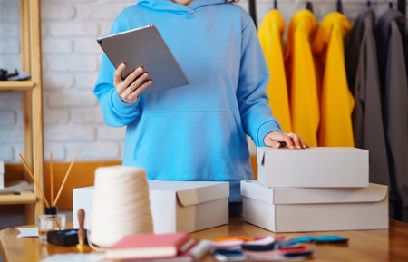 Small business owner, entrepreneur, seller using tablet checking ecommerce clothing store orders.の写真素材