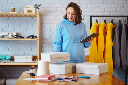 Small business owner, entrepreneur, seller using tablet checking ecommerce clothing store orders.の写真素材