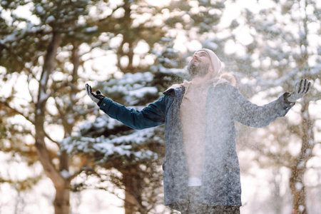 Portrait of young man in snowy winter forest. Season, christmas, travel and people concept.の写真素材