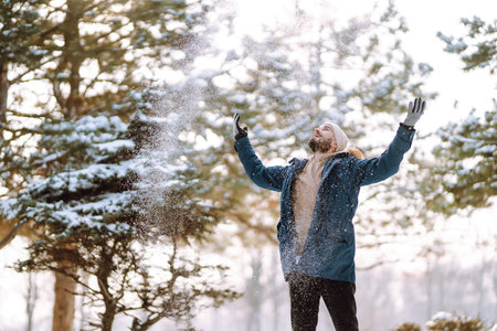 Portrait of young man in snowy winter forest. Season, christmas, travel and people concept.の写真素材