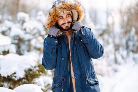 Portrait of young man in snowy winter forest. Season, christmas, travel and people concept.の写真素材