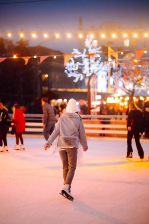 Young woman ice skating on the ice arena in the city square in winter on Christmas Eve. winter holiday.の写真素材