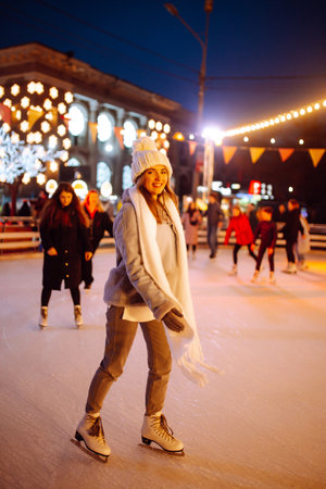 Young woman ice skating on the ice arena in the city square in winter on Christmas Eve. winter holiday.の写真素材