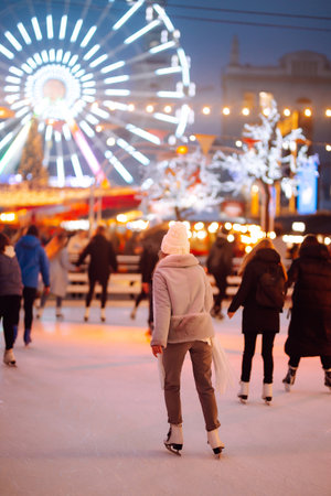 Young woman ice skating on the ice arena in the city square in winter on Christmas Eve. winter holiday.の写真素材