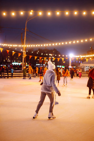 Young woman ice skating on the ice arena in the city square in winter on Christmas Eve. winter holiday.の写真素材