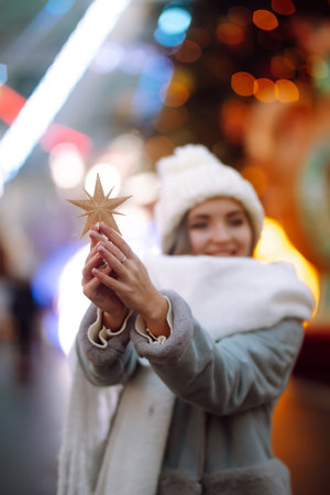Smiling woman in winter style clothes posing at festive street market. Young woman enjoying winter moments.の写真素材