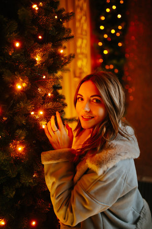 Smiling woman in winter style clothes posing at festive street market. Young woman enjoying winter moments.の写真素材