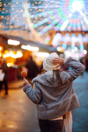 Young woman with caramel apple on Christmas market. Smiling woman in winter style clothes posing.の写真素材