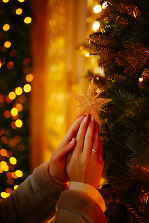 Young woman posing by the christmas tree at winter holidays. Light decorations in the streets.の写真素材