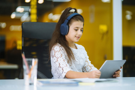 online education. Schoolgirl in headset sit at home desk watch education video lesson. homeschooler.の写真素材