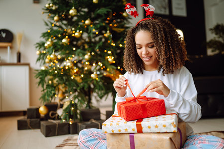 Portrait of young woman in santa claus hat with gift at the Christmas tree. Christmas. new year's.の写真素材
