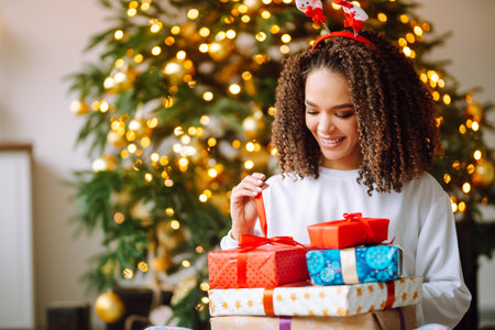 Portrait of young woman in santa claus hat with gift at the Christmas tree. Christmas. new year's.の写真素材