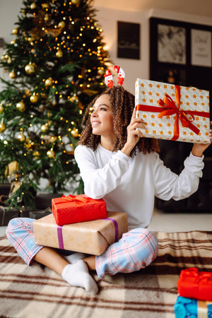 Portrait of young woman in santa claus hat with gift at the Christmas tree. Christmas. new year's.の写真素材