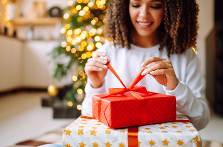 A young woman on the background of a Christmas tree with gifts, with a tablet has a video call or video chat.の写真素材