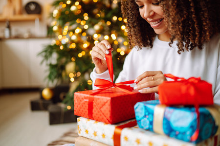 A young woman on the background of a Christmas tree with gifts, with a tablet has a video call or video chat.の写真素材