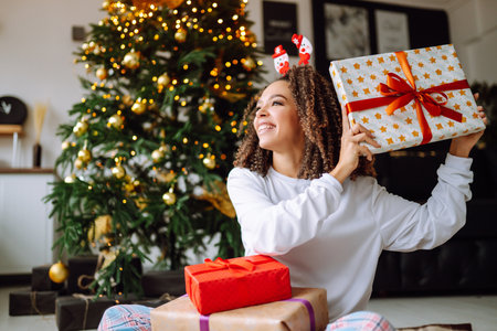 A young woman on the background of a Christmas tree with gifts, with a tablet has a video call or video chat.の写真素材