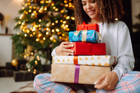 A young woman on the background of a Christmas tree with gifts, with a tablet has a video call or video chat.の写真素材