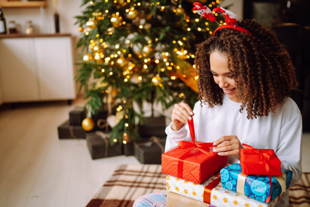 A young woman on the background of a Christmas tree with gifts, with a tablet has a video call or video chat.の写真素材