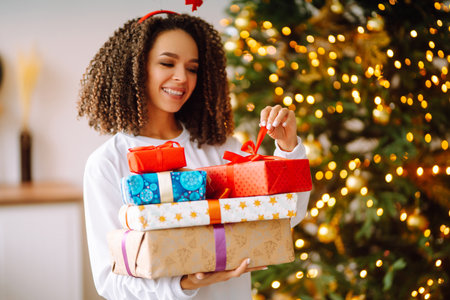A young woman on the background of a Christmas tree with gifts, with a tablet has a video call or video chat.の写真素材