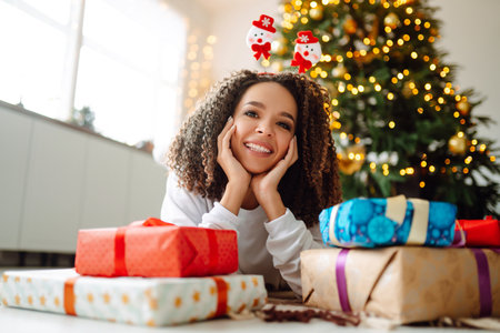 A young woman on the background of a Christmas tree with gifts, with a tablet has a video call or video chat.の写真素材