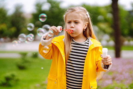 Cute little girl in the autumn on a walk blowing soap bubbles. Childhood, active rest, lifestyle concept.の写真素材