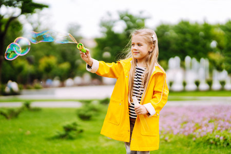Cute little girl in the autumn on a walk blowing soap bubbles. Childhood, active rest, lifestyle concept.の写真素材