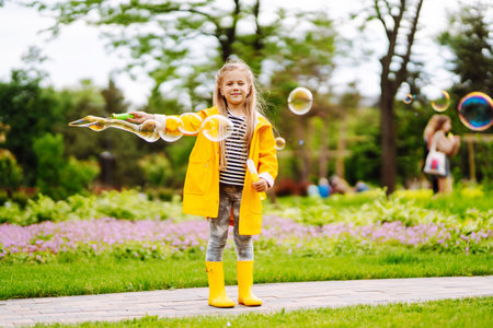 Cute little girl in the autumn on a walk blowing soap bubbles. Childhood, active rest, lifestyle concept.の写真素材
