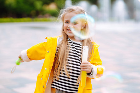 Cute little girl in the autumn on a walk blowing soap bubbles. Childhood, active rest, lifestyle concept.の写真素材