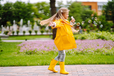 Cute little girl in the autumn on a walk blowing soap bubbles. Childhood, active rest, lifestyle concept.の写真素材