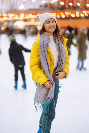 Happy woman ice skating on the ice arena in the city square on Festive Christmas fair. cold weather.の写真素材