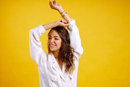 Portrait of young girl posing on yellow background. Pretty woman wears a carrot blouse and jeans.の写真素材